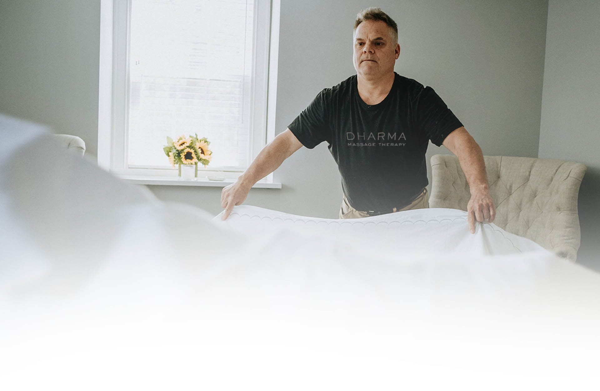 marks-journey-new Massage therapist setting up massage table with clean sheets